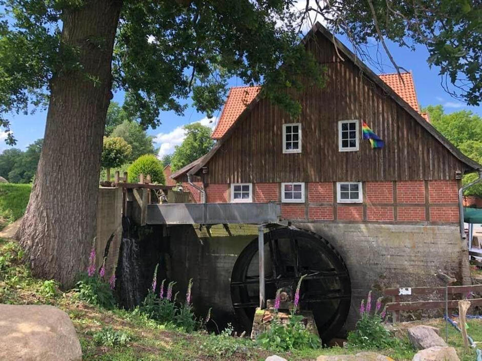 Außenansicht der historischen Wassermühle Bruchmühlen mit großem Wasserrad und liebevoll restauriertem Fachwerkgebäude.