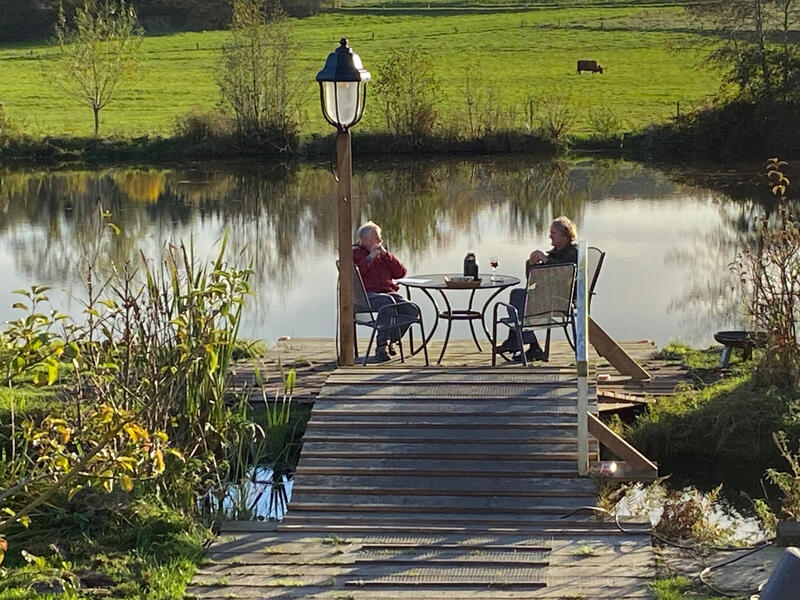 Gemütlicher Sitzplatz auf einem Holzsteg direkt am See der Wassermühle Bruchmühlen – ideal zum Entspannen und Genießen der Natur.