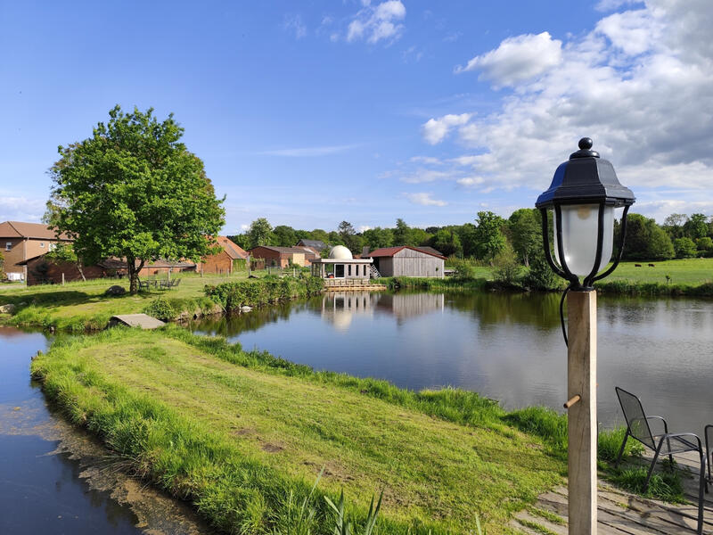Panoramablick auf die historische Wassermühle Bruchmühlen mit See, Wiesen und weitläufiger Naturkulisse.