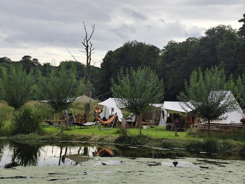 Zelte und gemütliche Sitzbereiche auf dem naturnahen Campingplatz direkt am See der Wassermühle Bruchmühlen.