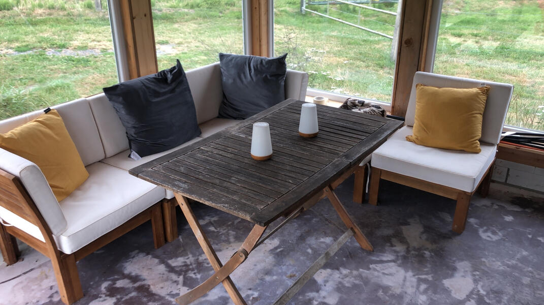 Überdachte Sitzecke mit gemütlichen Loungemöbeln und Blick ins Grüne – ideal zum Entspannen an der Bruchmühle.